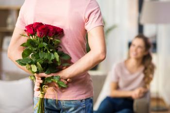 man holding flowers behind his back